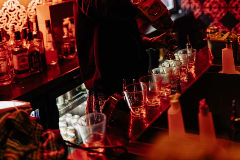 Carousel bartender pouring drinks under red bar lights