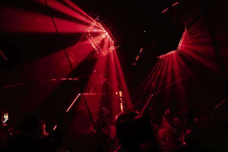 Mirrored Carousel light installation throwing red beams over the crowd
