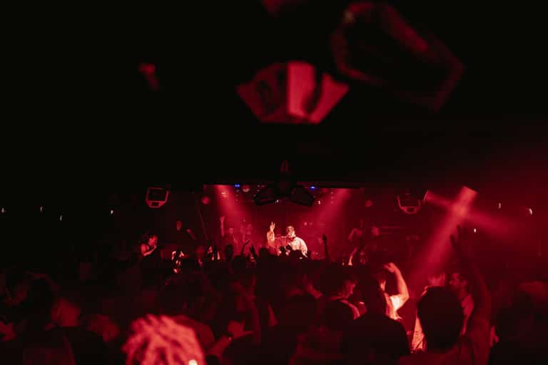 Performer leading the Carousel crowd under red light
