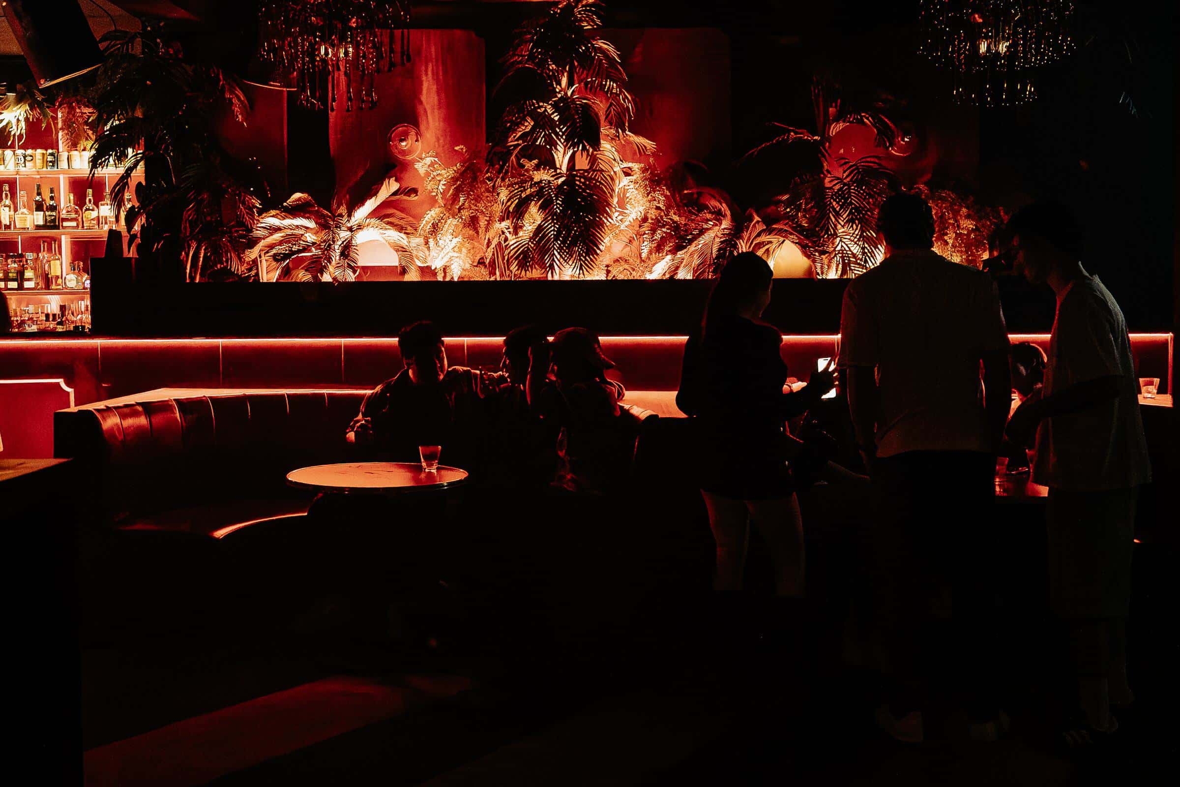 Red-lit Carousel lounge with guests beside the bar